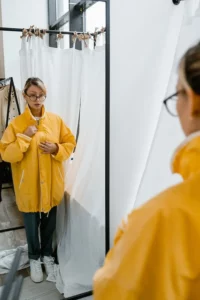 femme qui essaye des imperméables dans une cabine d'essayage